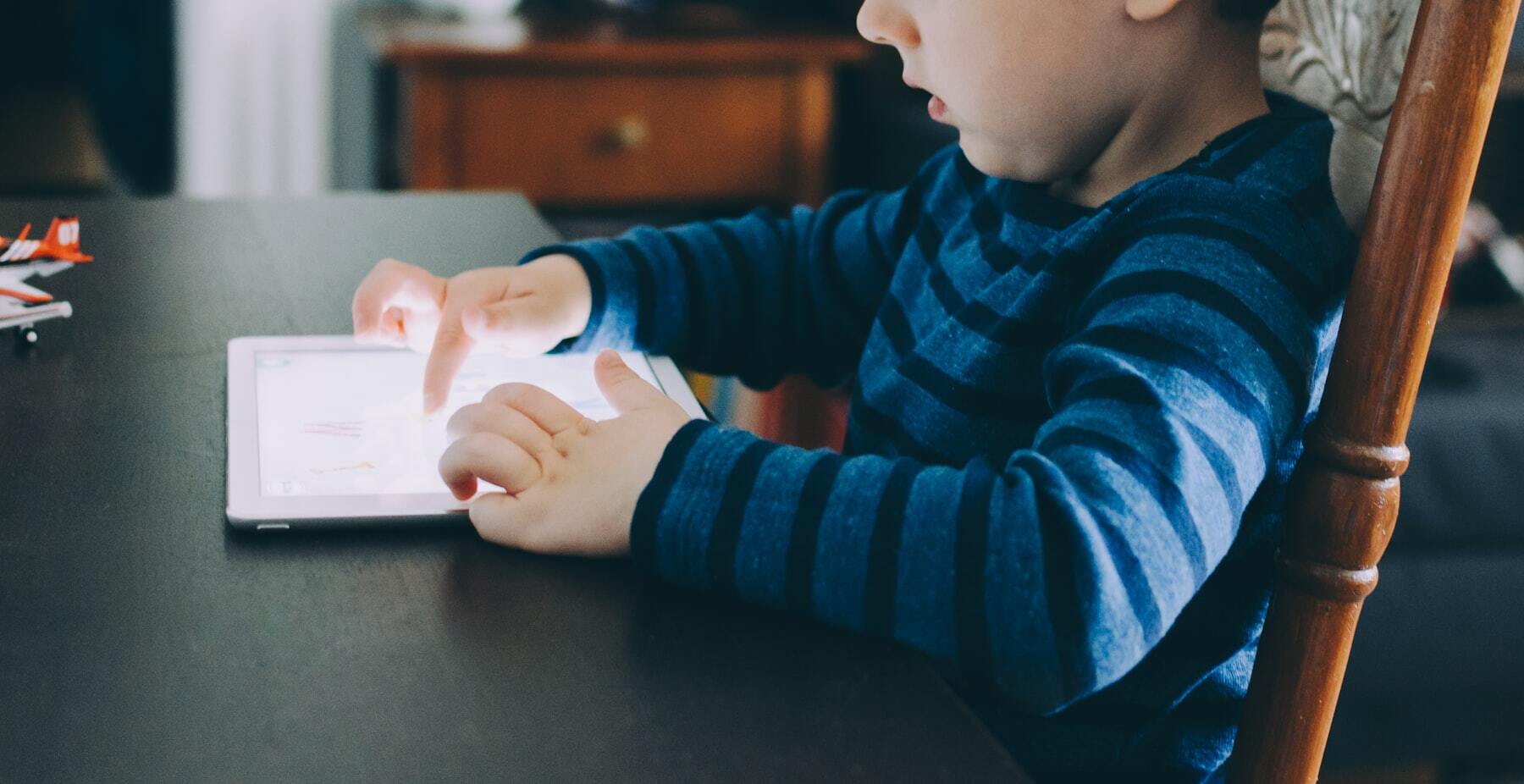 A young boy concentrates happily on a learning game on his tablet