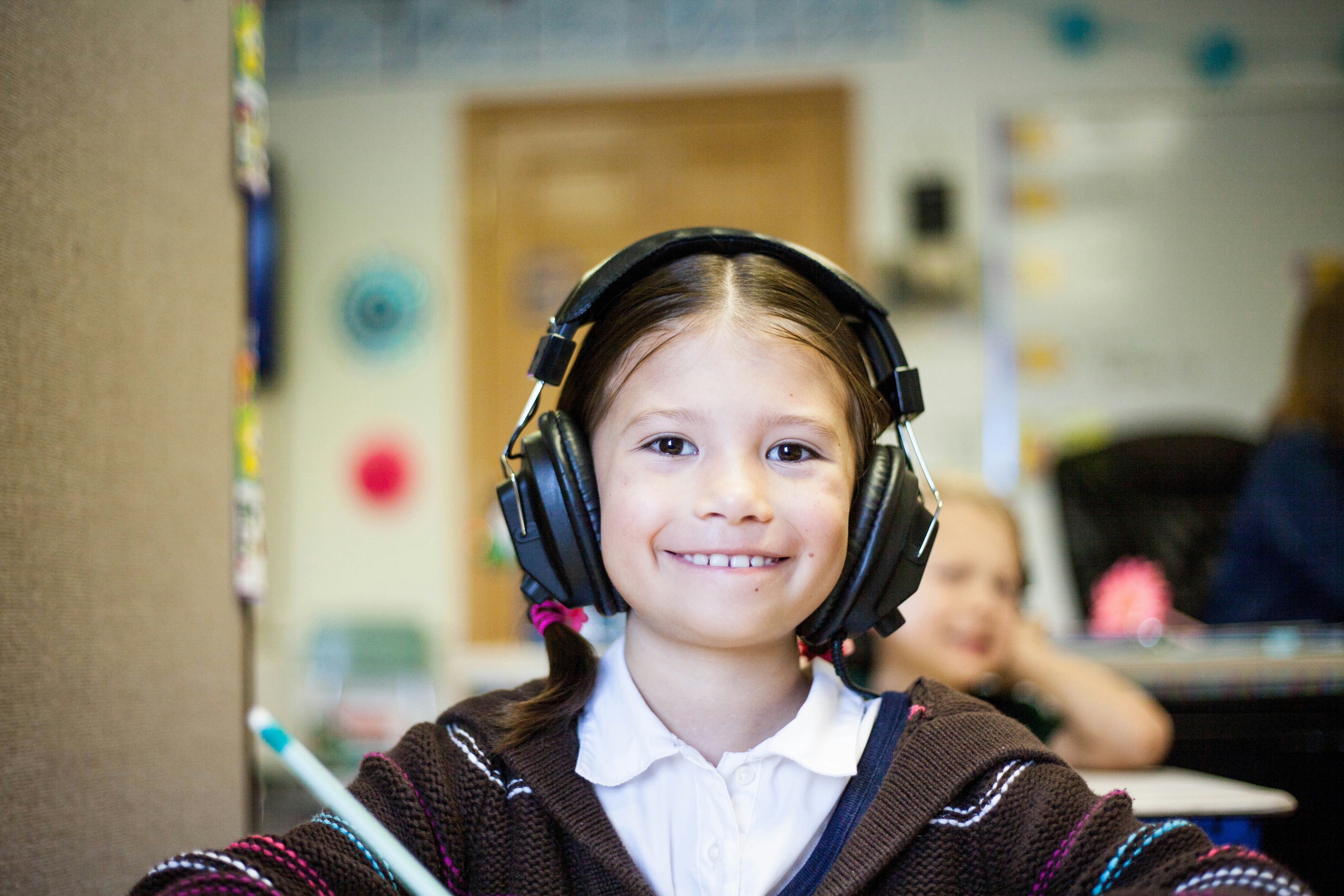 A young girl wearing headphones smiles during a recording session